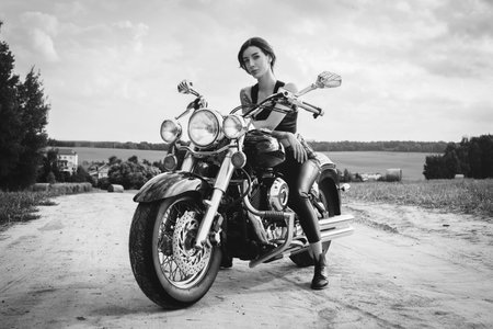 Young sexy girl posing on a motorcycle at sunset. Motor sport concept. Mixed mediaの写真素材