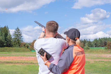 Man shoots plates with a hunting rifle in a competition under the supervision of an instructor. The concept of hunting, shooting competition.の写真素材