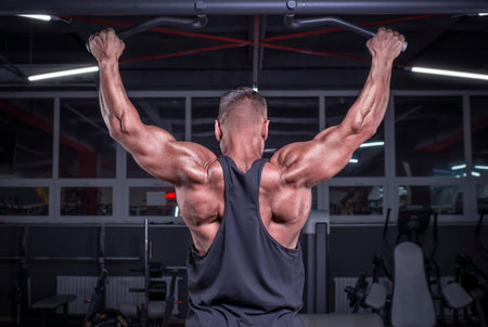 Image of a powerful athlete doing a pull-up in the gym. Back pumping. Fitness and bodybuilding...