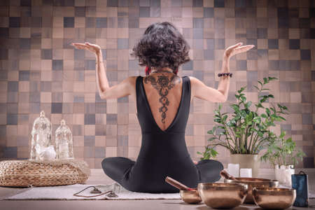 Image of an adult woman in yoga place. Meditation. Back view. The concept of yoga and spiritual practices. Mixed mediaの写真素材