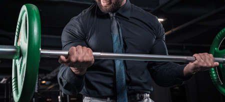 Stylish man in a business suit works out in the gym. Business and bodybuilding concept. Sports activities. Mixed mediaの写真素材
