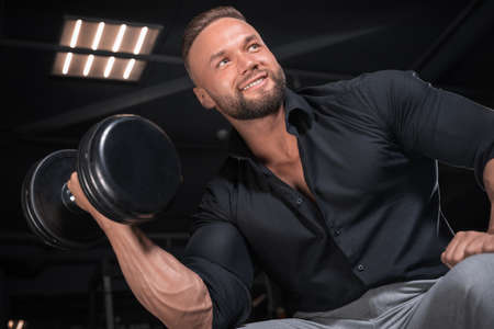 Stylish man in a business suit works out in the gym. Business and bodybuilding concept. Sports activities. Mixed mediaの写真素材
