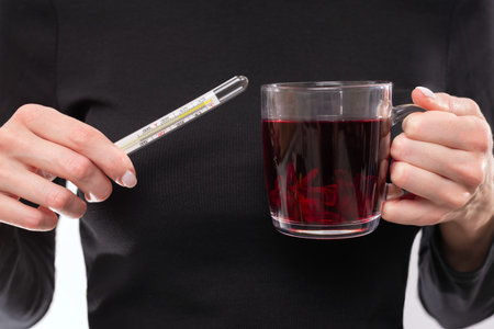 Image of female hands with a thermometer and a mug. Seasonal viral disease concept. Mixed media