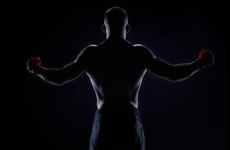 Kickboxer in red bandages raised his hands in victory. back view. The concept of mixed martial arts....
