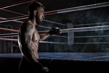 Kickboxer holding on to the ring rope. sports competitions. Fight night. The concept of mixed...