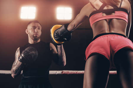 Athletic woman in red shorts and top is boxing with a trainer. Boxing and mixed martial arts concept. mixed mediaの写真素材