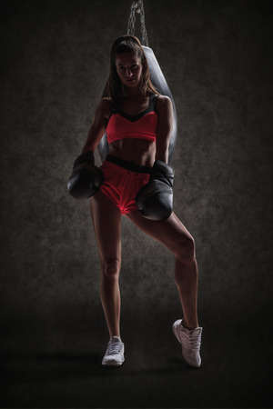 Athletic woman in red shorts and top posing near the bag. Boxing and mixed martial arts concept. mixed mediaの写真素材