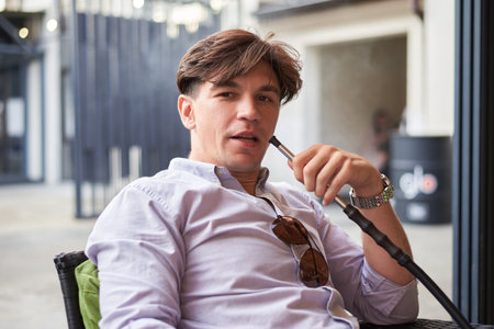 Image of a handsome man smoking a hookah in a lounge bar. vacation concept. mixed media
