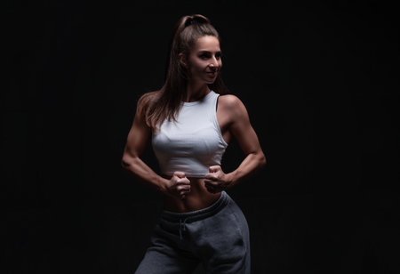 Athletic fitness woman posing in the studio on a dark background. Photo of an attractive woman in fashionable sportswear. Sports and healthy lifestyle. mixed mediaの写真素材