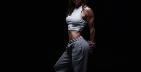 Athletic fitness woman posing in the studio on a dark background. Photo of an attractive woman in fashionable sportswear. Sports and healthy lifestyle. mixed mediaの写真素材