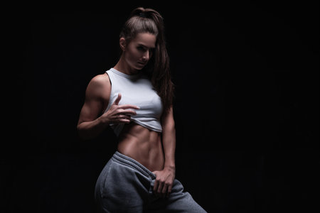 Athletic fitness woman posing in the studio on a dark background. Photo of an attractive woman in fashionable sportswear. Sports and healthy lifestyle. mixed mediaの写真素材