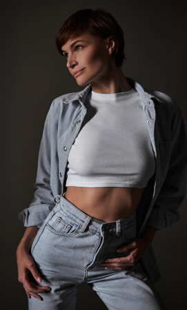 Athletic and sexy woman in a denim suit posing in the studio. perfect body. mixed mediaの写真素材