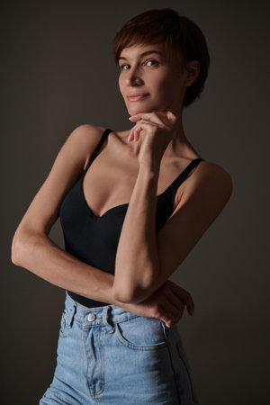 Athletic and sexy woman in a black bodysuit and blue jeans posing in the studio. perfect body. mixed mediaの写真素材