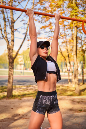 Beautiful young fitness girl is warming up at the stadium before training. Attractive slender...