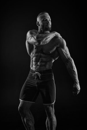 Silhouette of a strong bodybuilder. Confident young fitness athlete with a powerful body and perfect abs. Black and white photography. Dramatic light. Mixed mediaの写真素材
