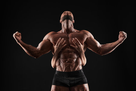 Perfect abdomen. Female hands embracing, touching muscular man abs isolated over black background. Sports, workout, bodybuilding concept. Front view. horizontal shotの写真素材