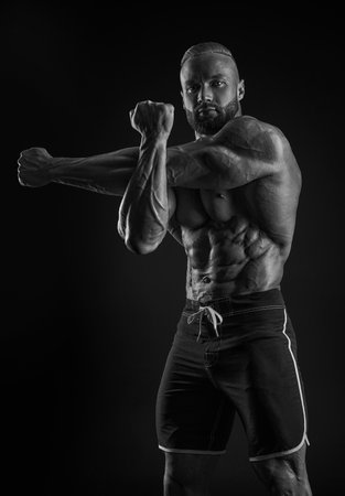 Silhouette of a strong bodybuilder. Confident young fitness athlete with a powerful body and perfect abs. Black and white photography. Dramatic light. Mixed mediaの写真素材