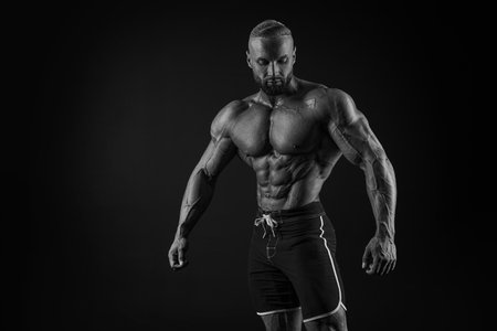 Silhouette of a strong bodybuilder. Confident young fitness athlete with a powerful body and perfect abs. Black and white photography. Dramatic light. Mixed mediaの写真素材