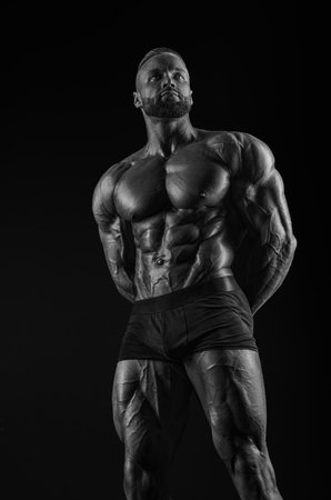 Silhouette of a strong bodybuilder. Confident young fitness athlete with a powerful body and perfect abs. Black and white photography. Dramatic light. Mixed mediaの写真素材