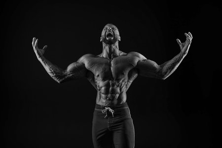Silhouette of a strong bodybuilder. Confident young fitness athlete with a powerful body and perfect abs. Black and white photography. Dramatic light. Mixed mediaの写真素材