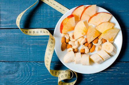 Healthy lifestyle. Apple and orange juice on a wooden background. Food for weight loss. Cereals. Tape measure.の写真素材