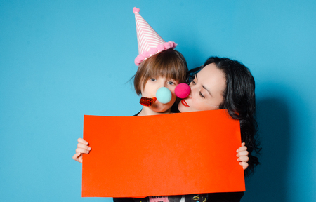 Happy mother with her daughter holding a red sheet of paper with the inscription April Fool's Day. Spring day is a fool. The concept of a holidayの写真素材