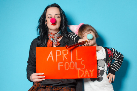Mom and daughter celebrate their birthday. Festive outfits. The concept of a holiday. Daughter and mother mimic in the hands of an empty leafの写真素材