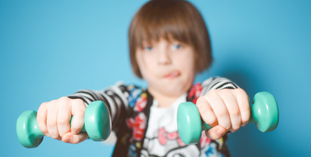 Cute little girl is lifting dumbbells. The concept of sports. Healthy lifestyle.の写真素材