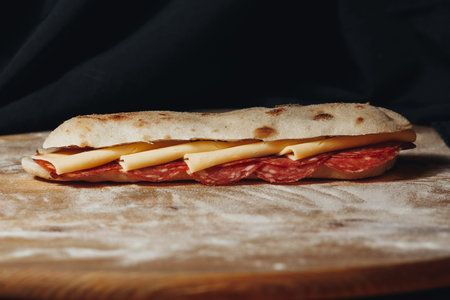 Artisanal Pepperoni and Cheese Sandwich on a Wooden Cutting Boardの写真素材