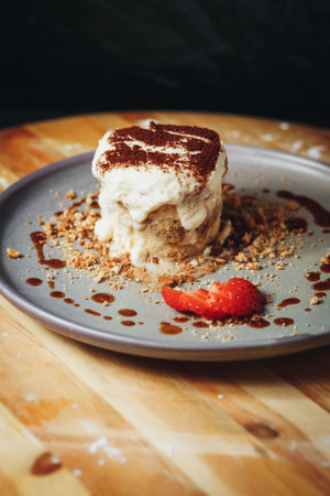 Delectable Tiramisu Served on a Ceramic Plate Garnished With Strawberry and Cocoaの写真素材