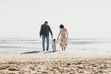 Serene Stroll: Family Walks Along Beach With Childの写真素材