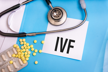 IVF word written on medical blue folder with patient files, pills and stethoscope on backgroundの写真素材