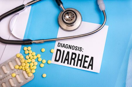 Diarhea word written on medical blue folder with patient files, pills and stethoscope on backgroundの写真素材