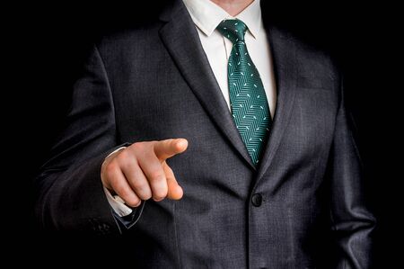 Business man is pointing his finger at you - isolated on black backgroundの写真素材