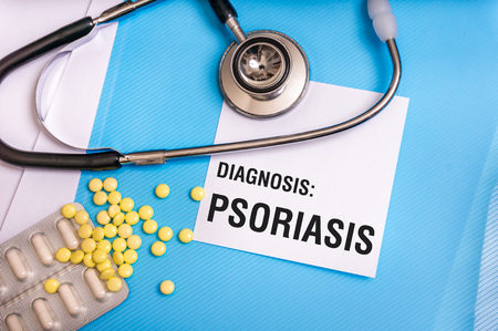 Psoriasis word written on medical blue folder with patient files, pills and stethoscope on backgroundの写真素材