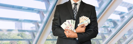 Businessman in suit with Czech and European money in office