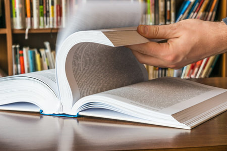 The hand of a man opening and browsing the book pages
