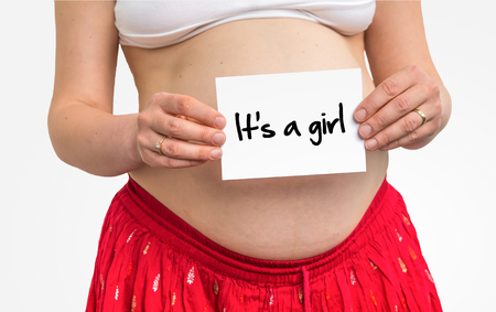 Pregnant woman with inscription: It's a girl on her bellyの写真素材