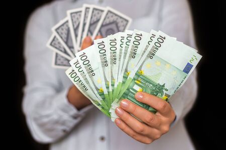 Gambler with cards and euro money banknotes isolated on black backgroundの写真素材