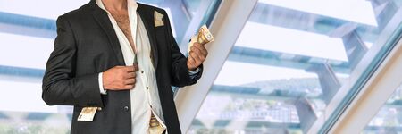 Disheveled businessman in a black suit and money in pockets in officeの写真素材