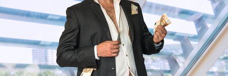 Disheveled businessman in a black suit and money in pockets in officeの写真素材