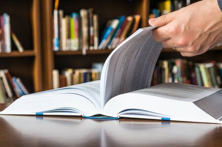 The hand of a man opening and browsing the book pagesの写真素材