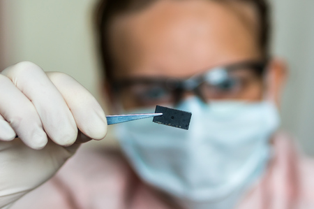 Young scientist holding and examining damaged electrical chipの写真素材
