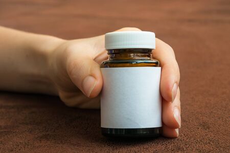 Human hand holding a bottle of pills with white blank labelの写真素材