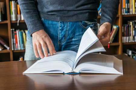 The man opening and browsing the book pages in library