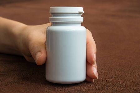 Human hand holding a bottle of pills with white blank labelの写真素材