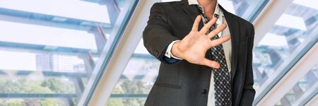 Man in suit gestures leave me alone in officeの写真素材