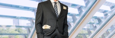 Man in business suit with money in pockets in officeの写真素材