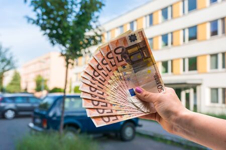 Property buyer holding euro banknotes and buying beautiful flat from real estate agencies on blurred backgroundの写真素材