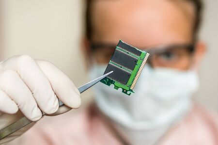 Young scientist holding and examining damaged electrical componentの写真素材